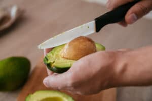 Open avocado by cutting it in half and use the knife to remove the nut.